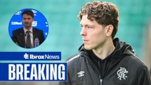 Andreas Skov Olsen in a Rangers coat looking towards Danny Rohl speaking in a Rangers press conference